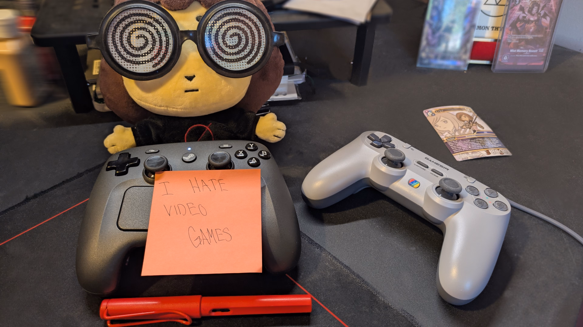 a milk girl plush sits behind the Steam controller and a Gamesir controller. A post-it note prominently reads, "I HATE VIDEO GAMES"